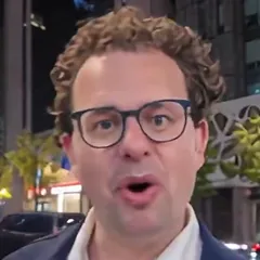 Curly-haired man in glasses and a navy blazer