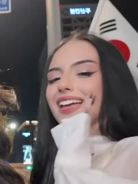 The friend on the right of the group selfie, long black hair and a white blouse, Korean flag behind